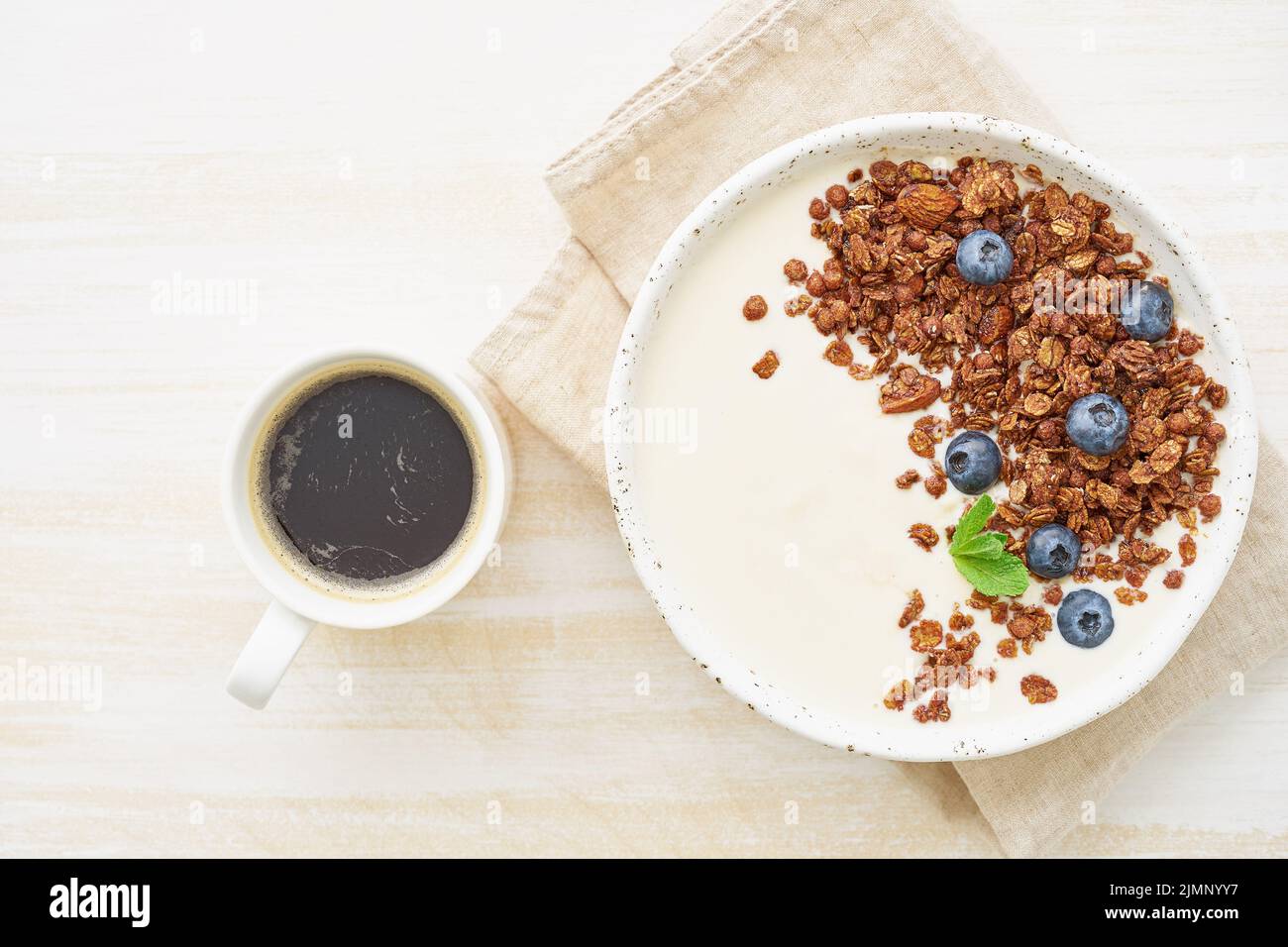 Yogurt with chocolate granola, bilberry. Breakfast with cupof coffee on a white background Stock Photo