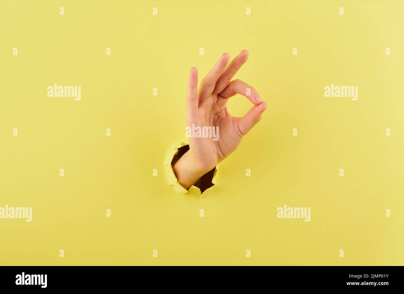 Woman showing a sign of agreement on yellow background copy space closeup Stock Photo