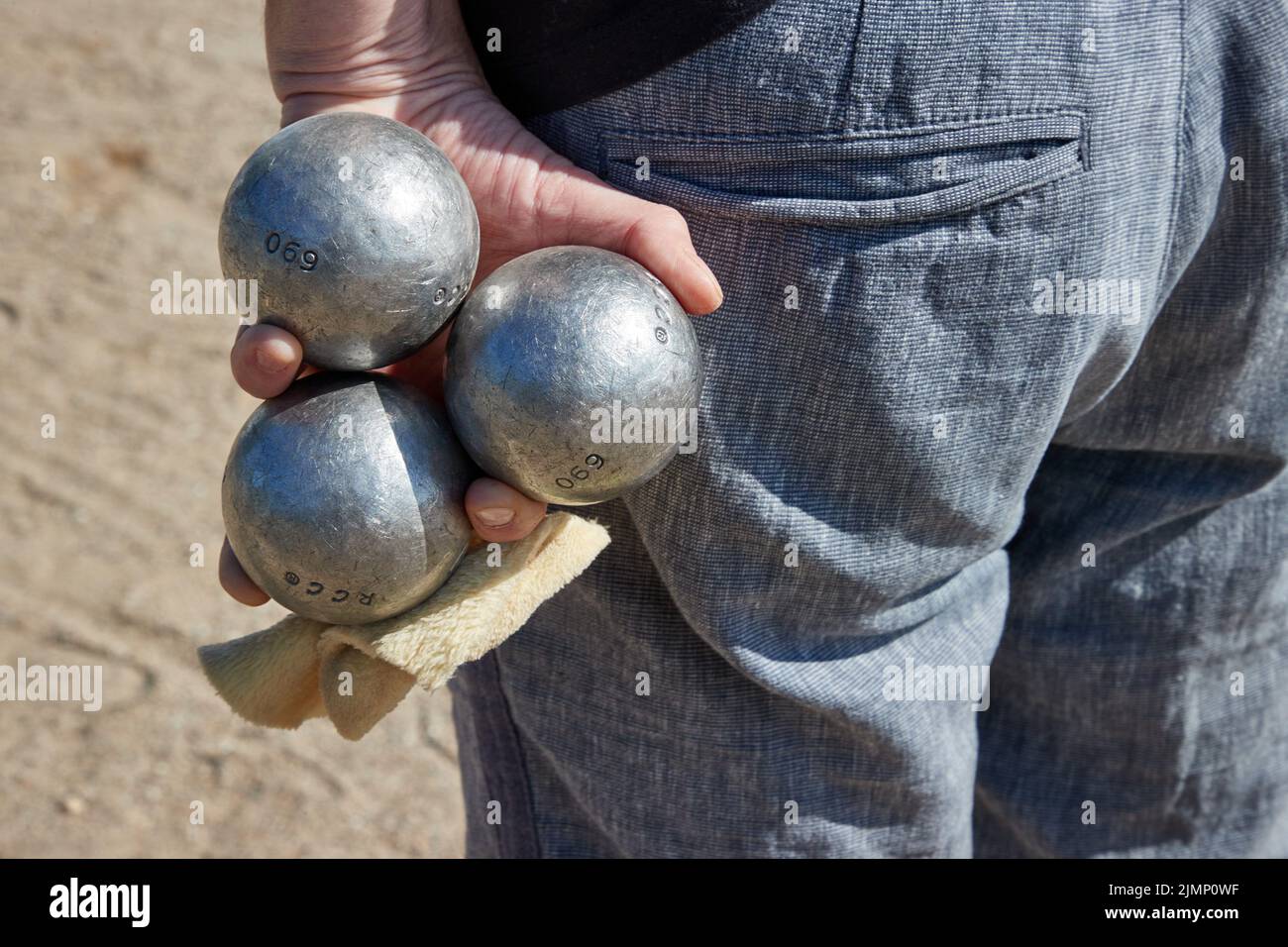 07 August 2022, Schleswig-Holstein, Lübeck: A participant holds three boules balls in his hand. The Holstentorturnier is considered the largest German boules tournament. Photo: Georg Wendt/dpa Stock Photo