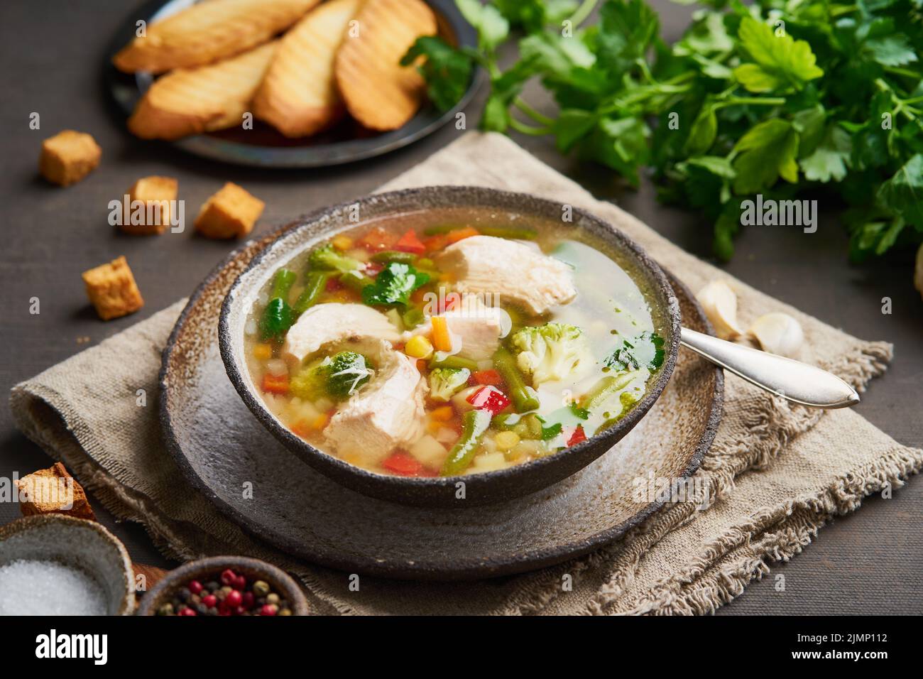 Homemade chicken soup with vegetables, crouton, broccoli on a dark brown background, side view Stock Photo