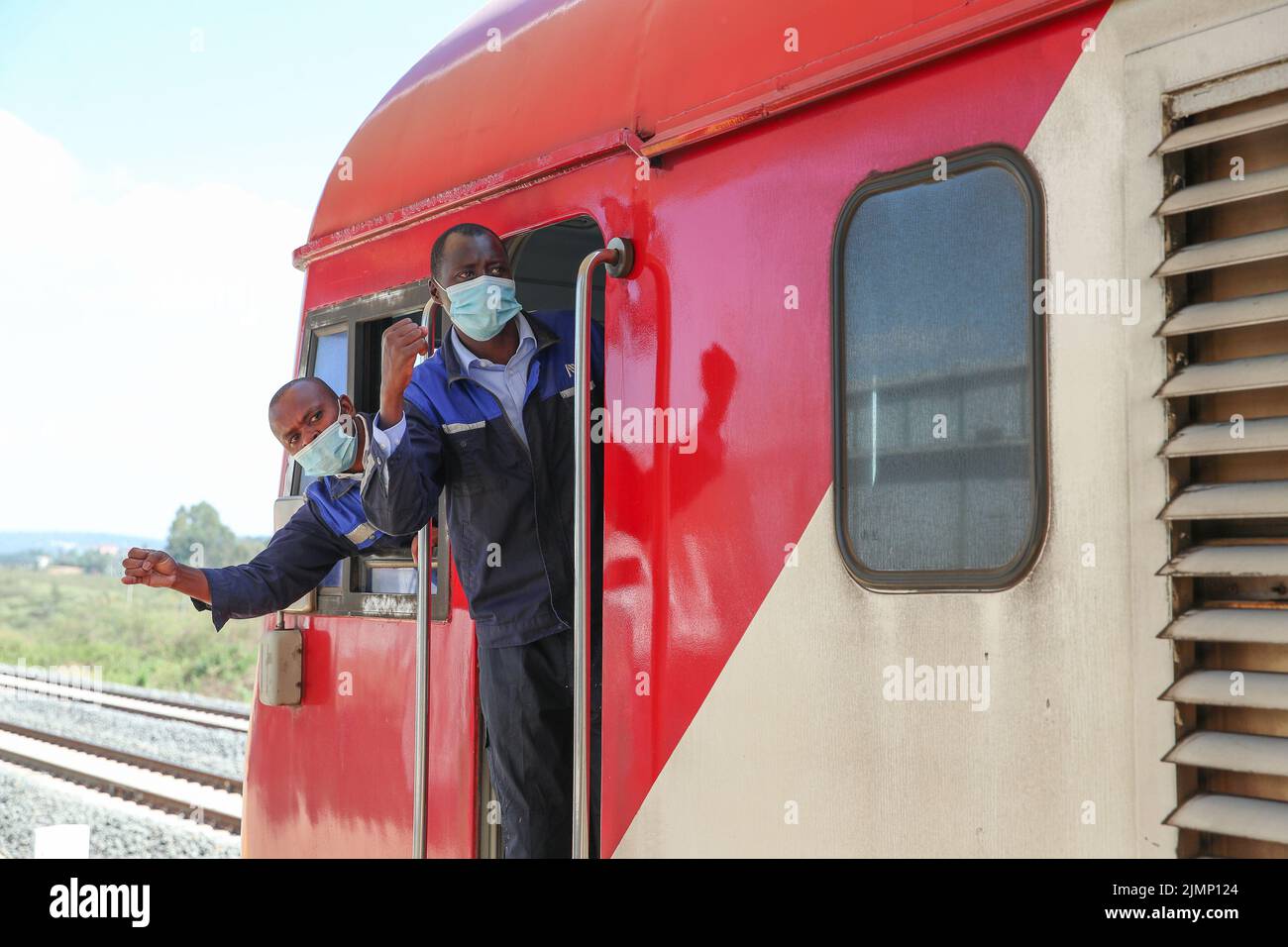 (220807) -- NAIROBI, Aug. 7, 2022 (Xinhua) -- Kenyan drivers John Pius (L) and Brian Kemboi confirm safety with platform staff at Ngong station in Kajiado, Kenya, March 25, 2022. Launched on May 31, 2017, the 480 km Mombasa-Nairobi Standard Gauge Railway (SGR), financed mainly by China and constructed by China Road and Bridge Corporation (CRBC), has fostered job creation for local people.    Afristar, the company operating the SGR, has employed Kenyans in 123 railway professions which fall under 5 railway departments, including railway transportation, locomotive, track, signal, and rolling sto Stock Photo