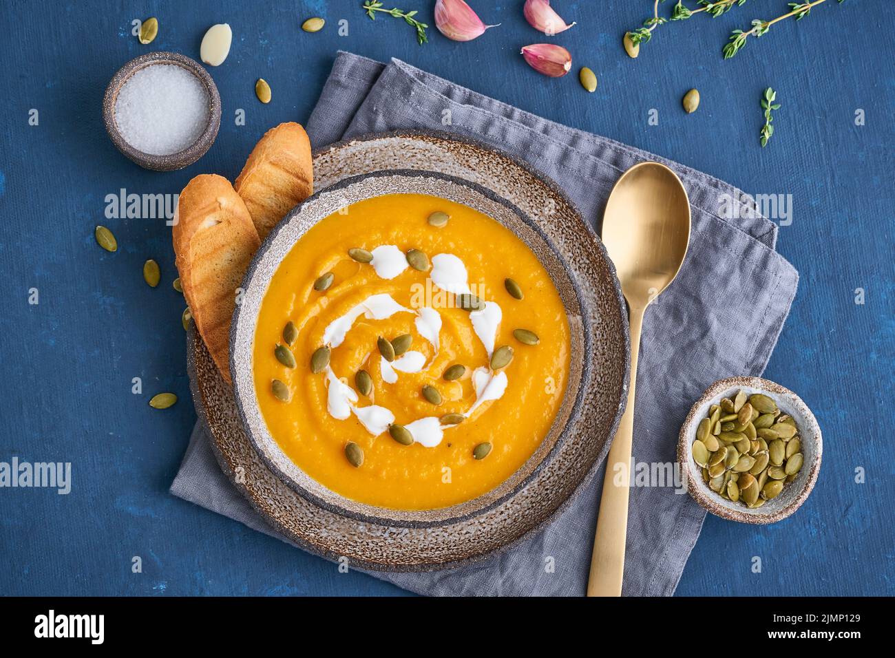 Pupmkin cream soup puree on dark blue wooden table, dietary vegetarian lunch, top view. Stock Photo