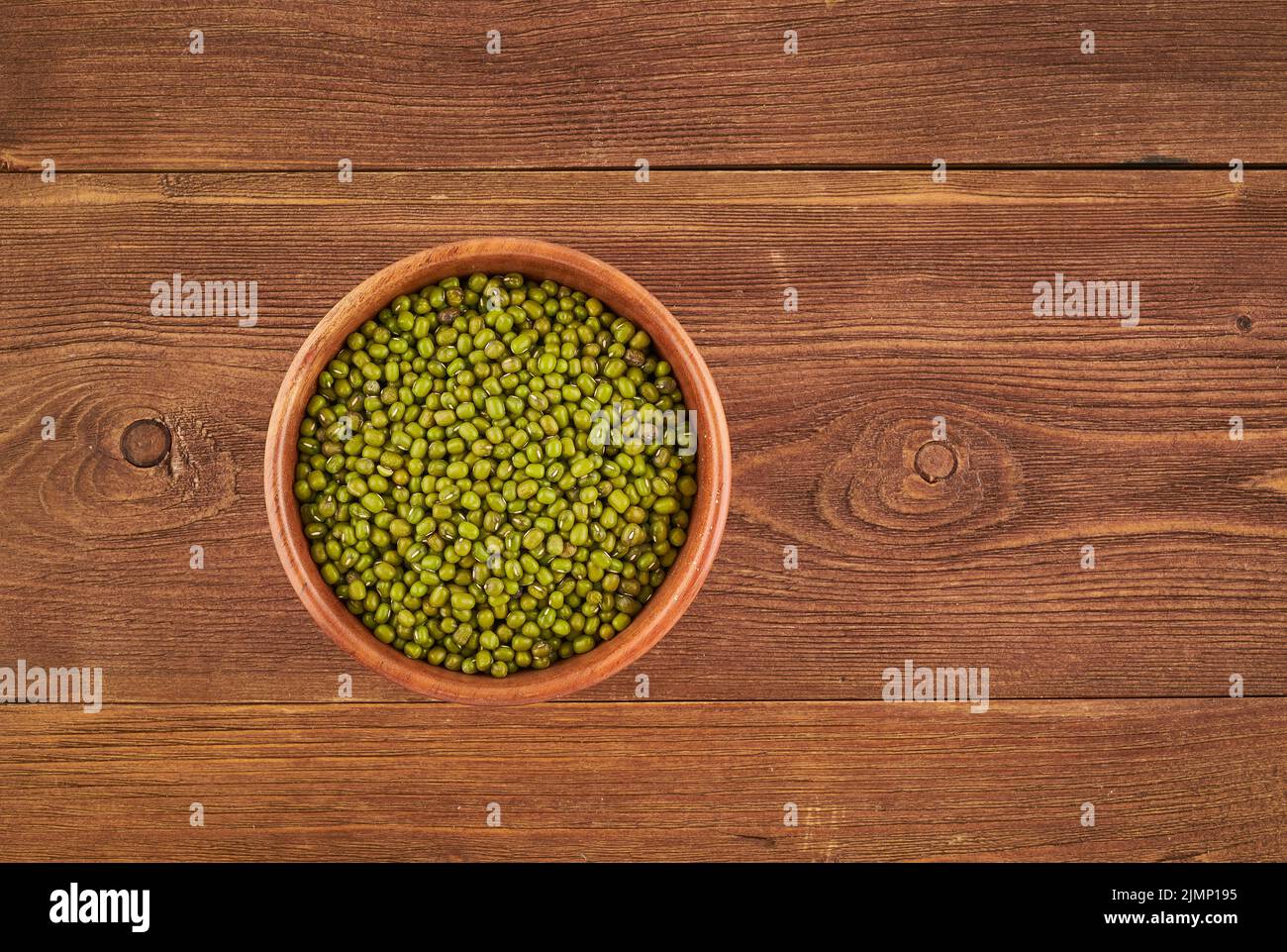Mung beans in wooden bowl on brown background, top view, copy space Stock Photo