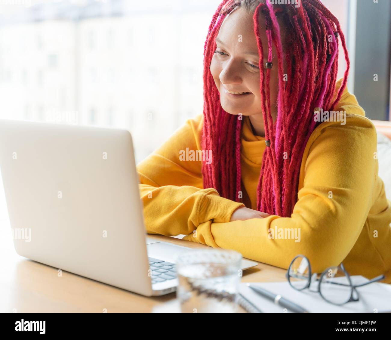 Digital nomad concept. Girl freelancer remotely working on laptop in cafe, coworking. Stock Photo