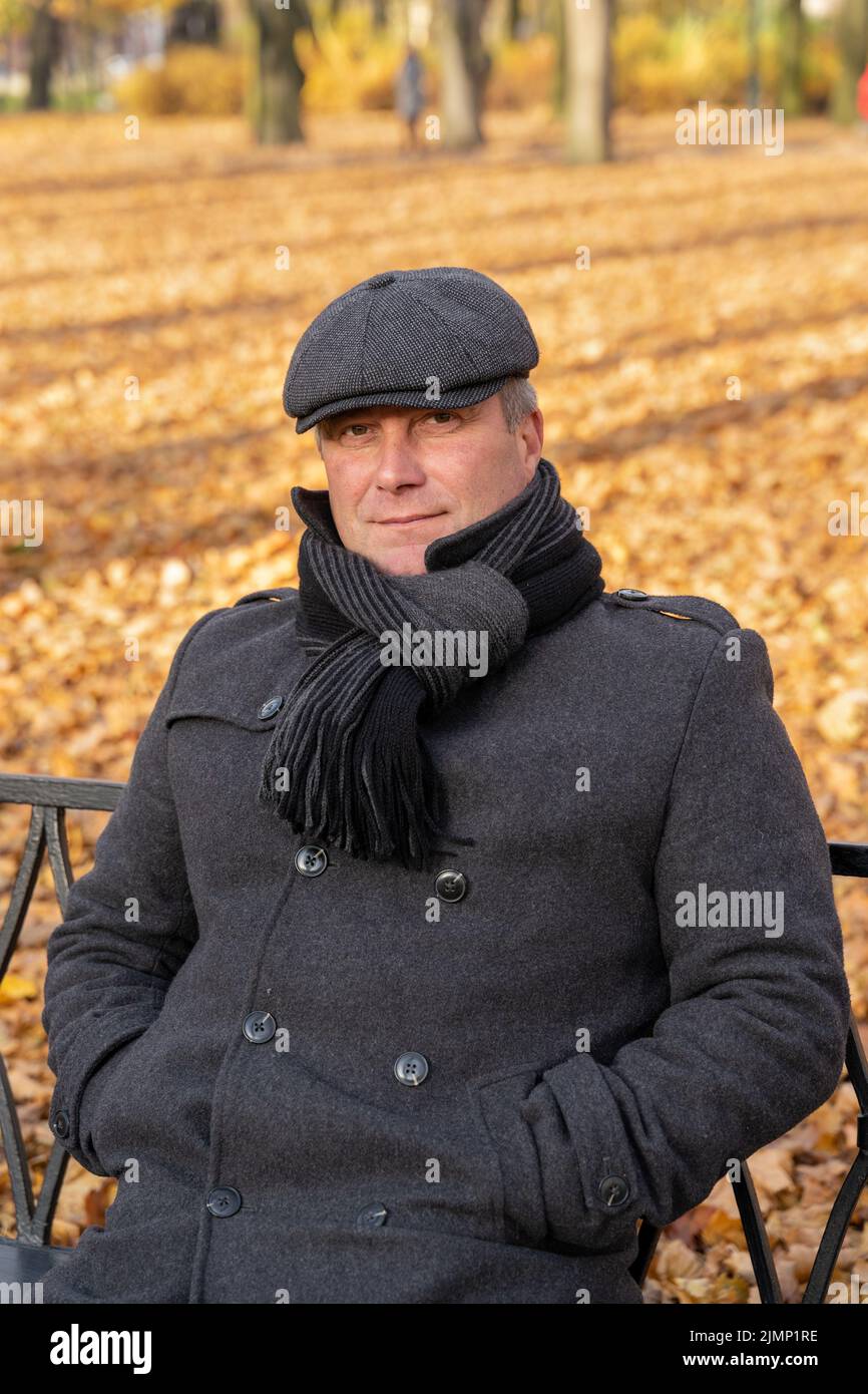 Closeup portrait of a beautiful middle-aged brunette. Mature handsome man of 45-50 years old walks in the autumn park in warm clothes, in a coat and e Stock Photo