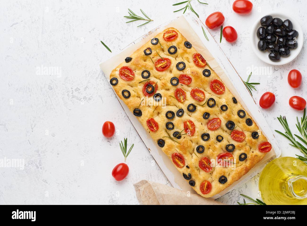 Focaccia with tomatoes, olives and rosemary, copy space, top view. Whole Italian flat bread, Stock Photo