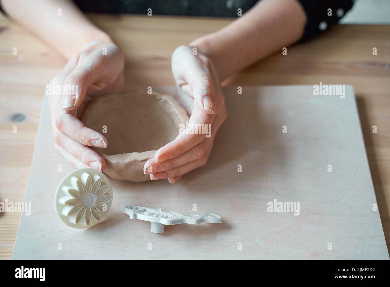 Woman making pottery, hands closeup, blurred background, focus on