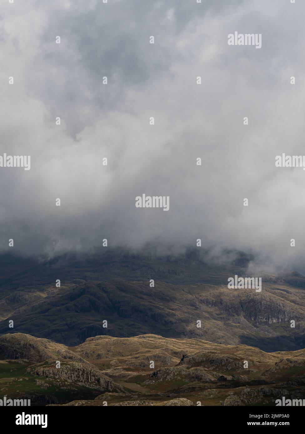 Dramatic looming grey clouds over mountains, view of the Lake District Stock Photo