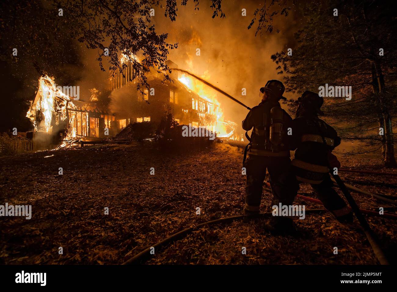 A two-man hose team uses a hose to spray water onto the fully engulfed home as at 0404 Hrs. on Thursday, November 1st, 2012, the Bridgehampton Fire De Stock Photo