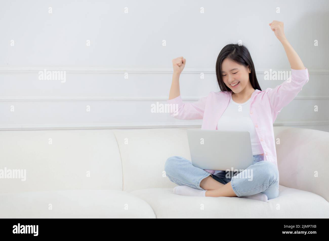 Happiness young asian woman sitting on sofa and working on laptop ...
