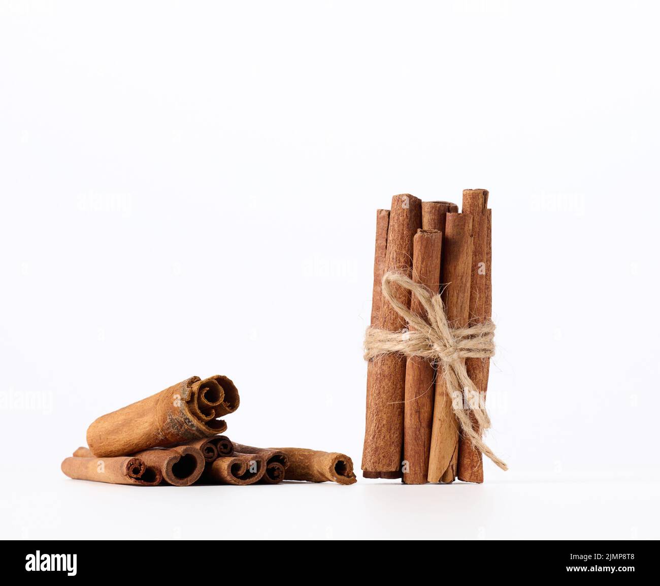 Dry cinnamon sticks tied with a rope on a white background Stock Photo