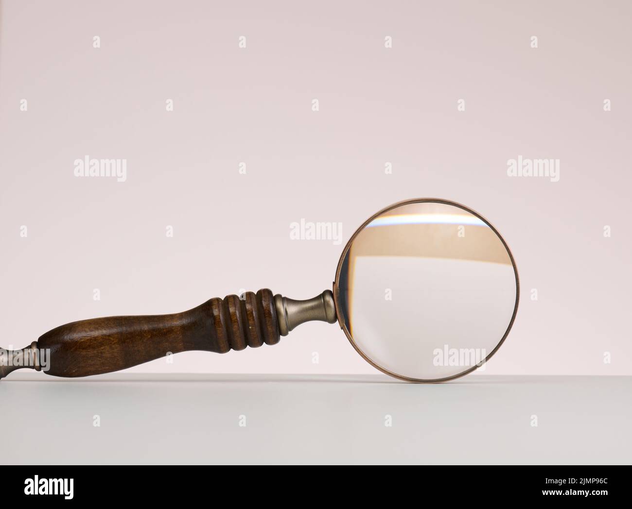 Wooden magnifier on a white background. The concept of uncertainty and the search for solutions, doubts Stock Photo