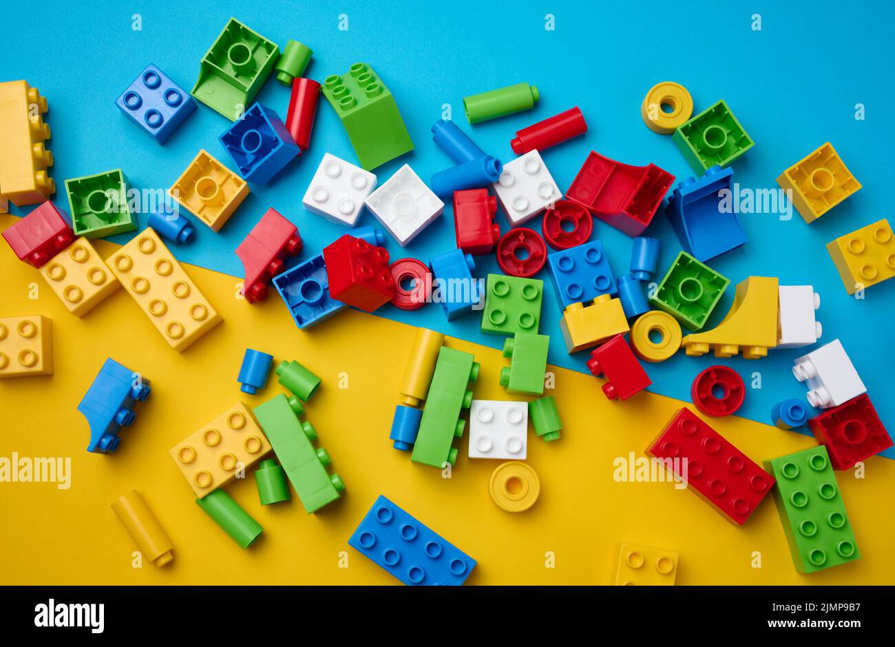 Scattered parts of a plastic children's designer, top view. Yellow blue background Stock Photo