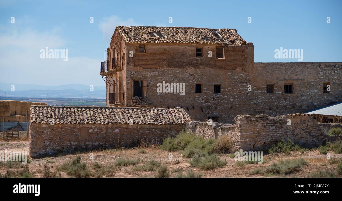 semi-derelict Spanish farmhouse and outbuildings in harsh midday sunlight, blue sky Stock Photo