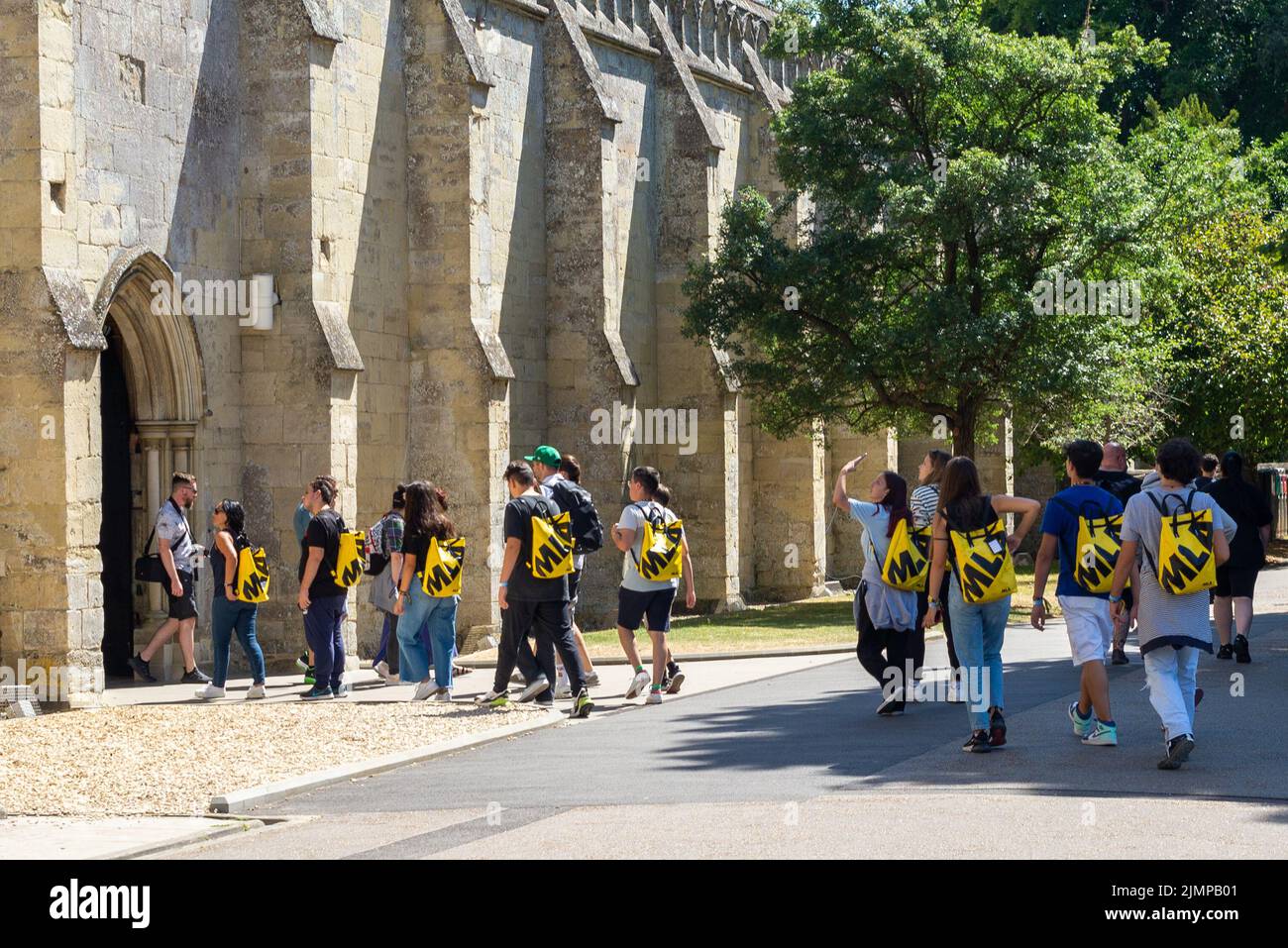 Salisbury, Wiltshire, UK, 7th August 2022, Weather: Hot sunshine in the cathedral city as another heatwave builds. A tour group with matching yellow rucksacks file into the cathedral visitor’s entrance. Credit: Paul Biggins/Alamy Live News Stock Photo