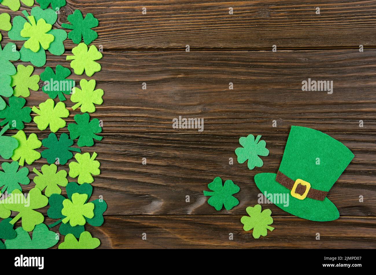 Happy Saint Patrick's mockup of handmade felt hat and shamrock clover leaves on wooden background. Stock Photo