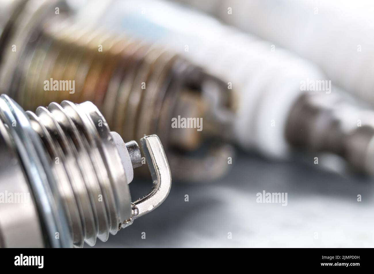 New and used spark plugs for internal combustion engine on metal background. Space for text Stock Photo