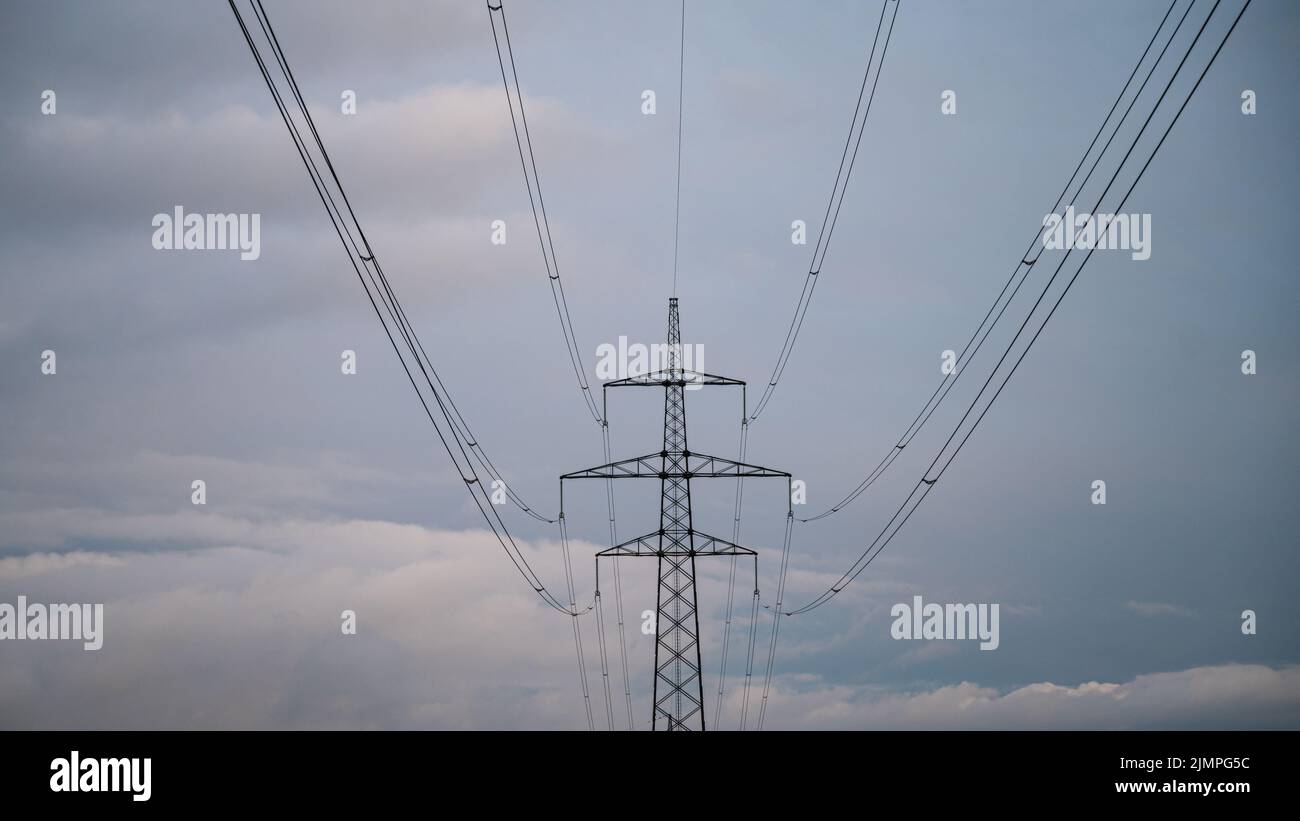 Electrical tower and wires running uner a cloudy sky. Stock Photo