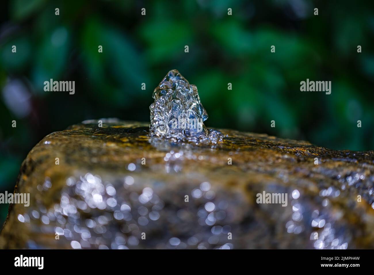 Water frozen in motion gushes out of a water stone Stock Photo