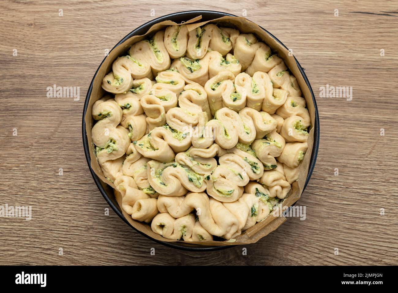 https://c8.alamy.com/comp/2JMPJGN/raw-homemade-round-bread-with-garlic-butter-and-herbs-in-a-round-baking-tin-2JMPJGN.jpg