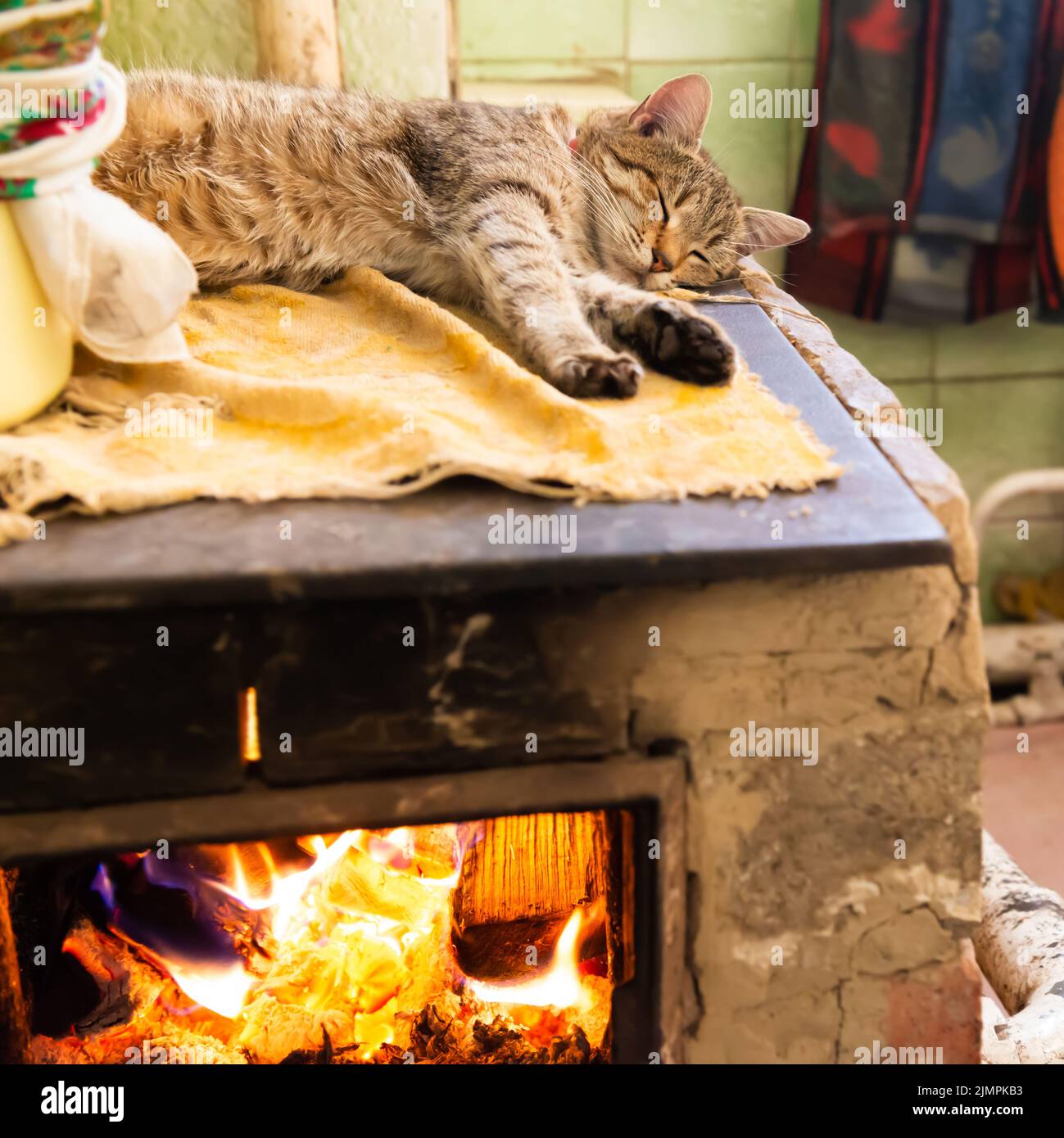 Cat sleeping on stove fireplace Stock Photo