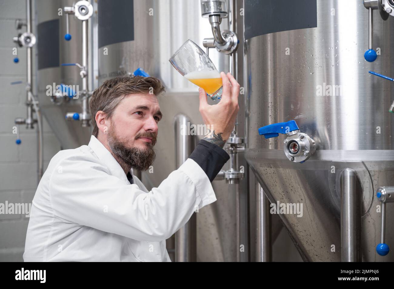 Brewer wearing white coat controlling process of beer fermentation
