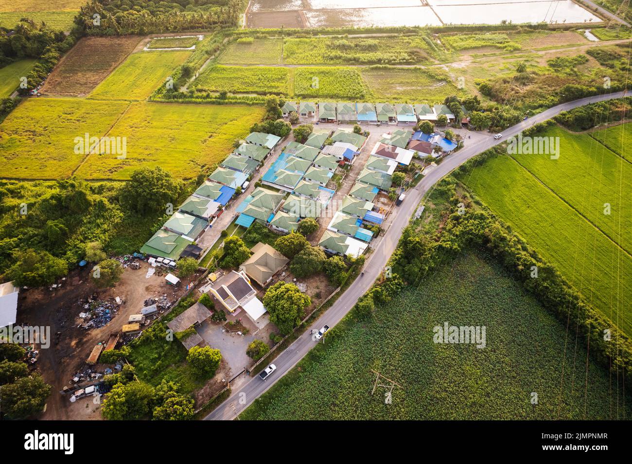 Aerial view of housing estate village with the road through rice field ...