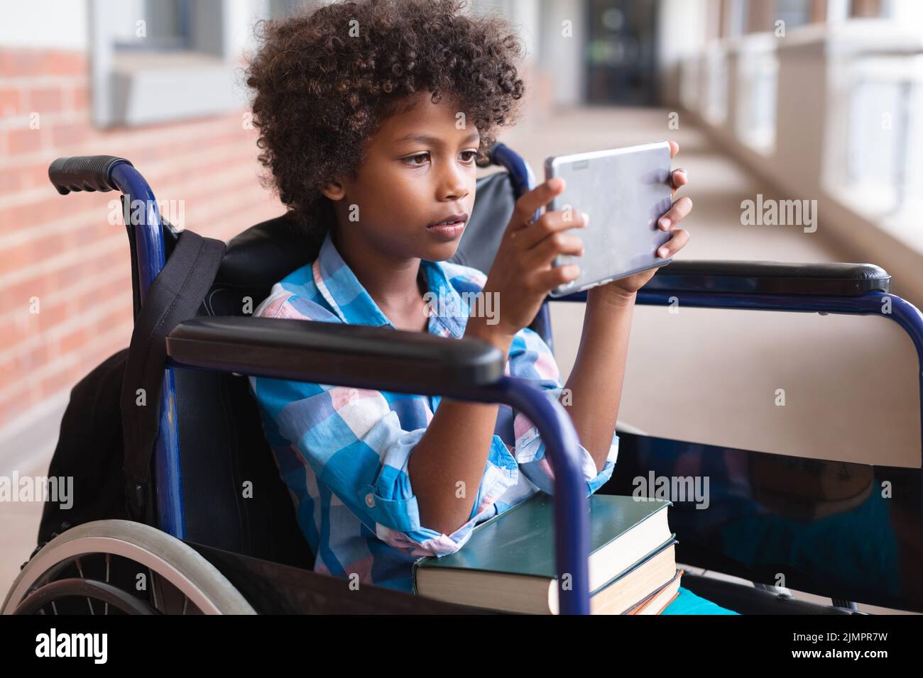 African american elementary schoolboy using digital tablet while ...