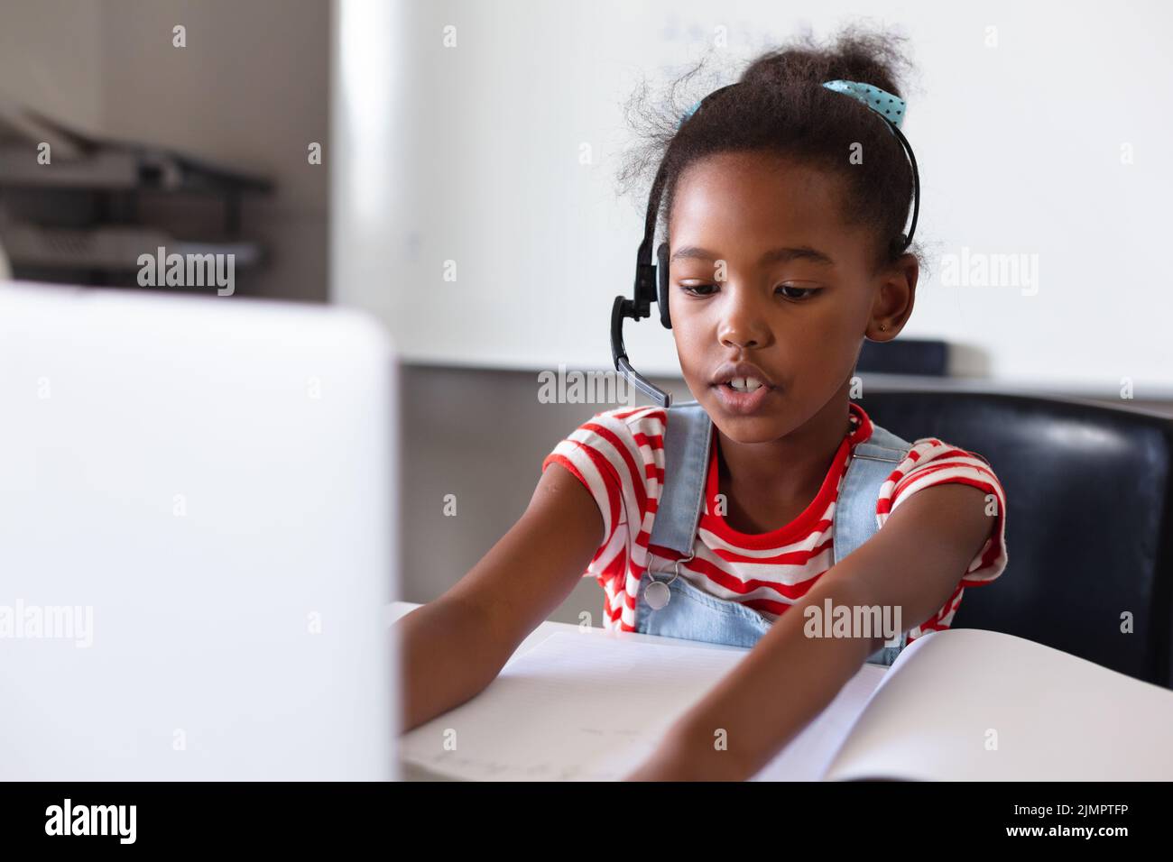 African american elementary schoolgirl wearing headphones while using ...