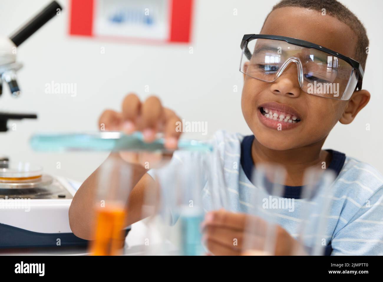 Smiling african american elementary schoolboy performing chemistry ...
