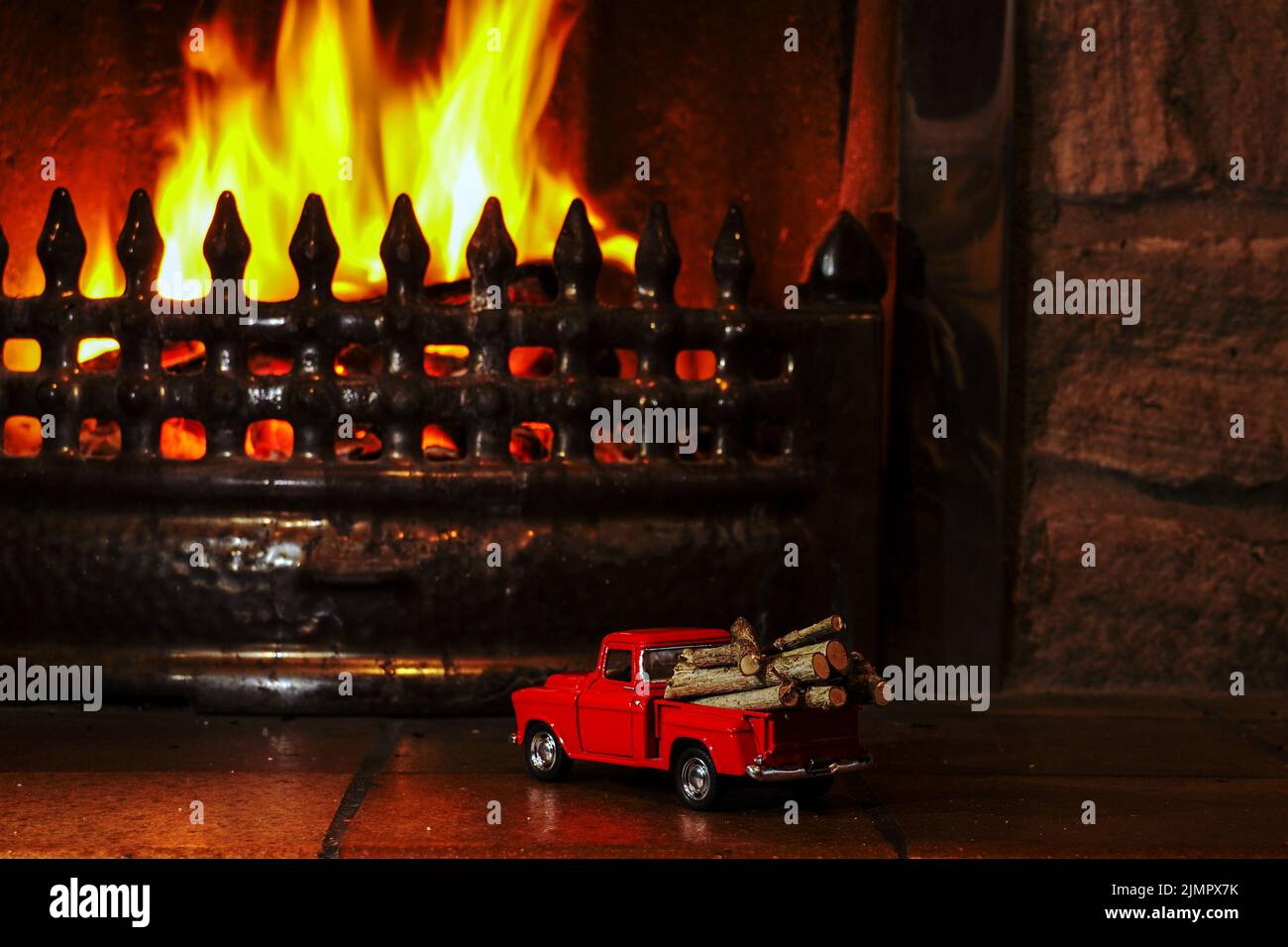 Red toy pickup truck delivers fire logs to the fireplace Stock Photo