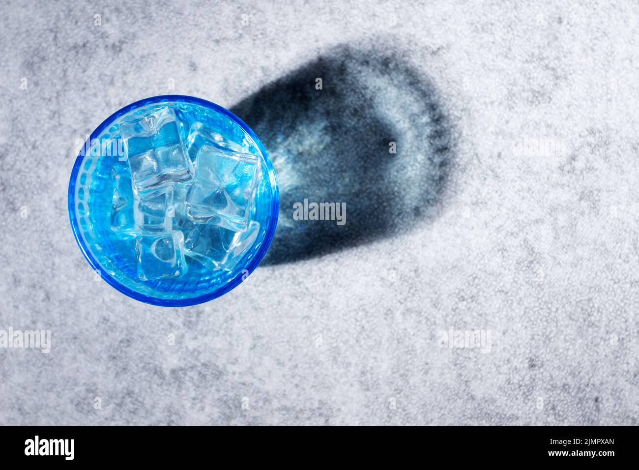 top view of blue glass with ice cubes and water projecting a reflexion ...