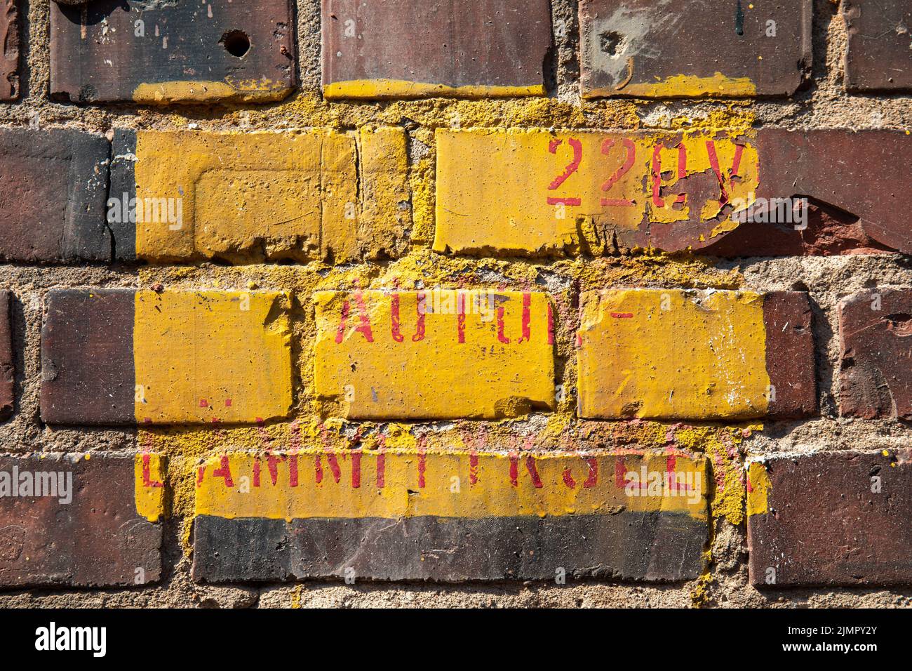 Red text on yellow square on red brick wall Stock Photo