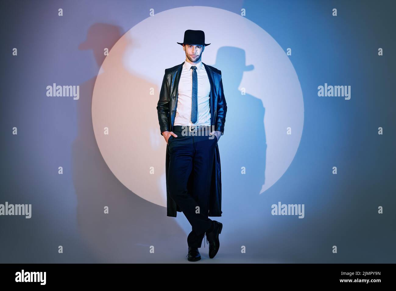 Full length portrait of handsome man in black coat and hat posing on ...