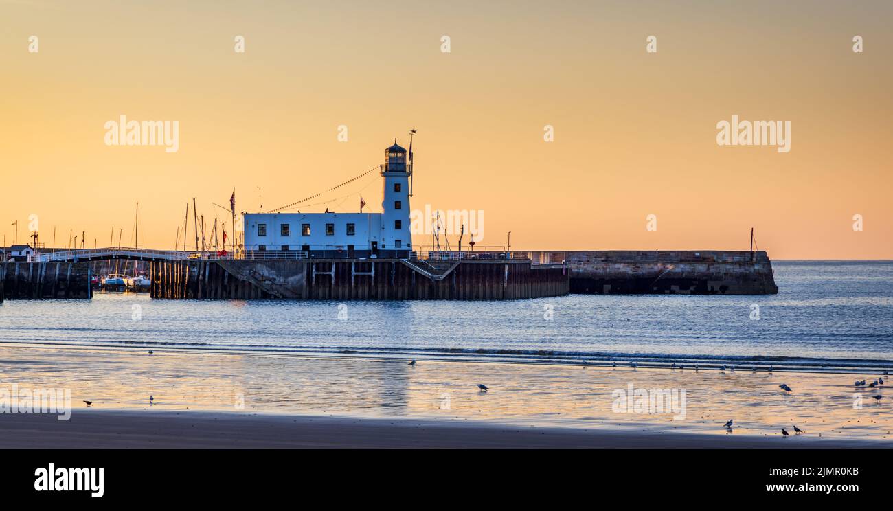 The start of a beautiful day with a view towards the harbour and lighthouse at Scarborough on the North Yorkshire coast, England. Stock Photo