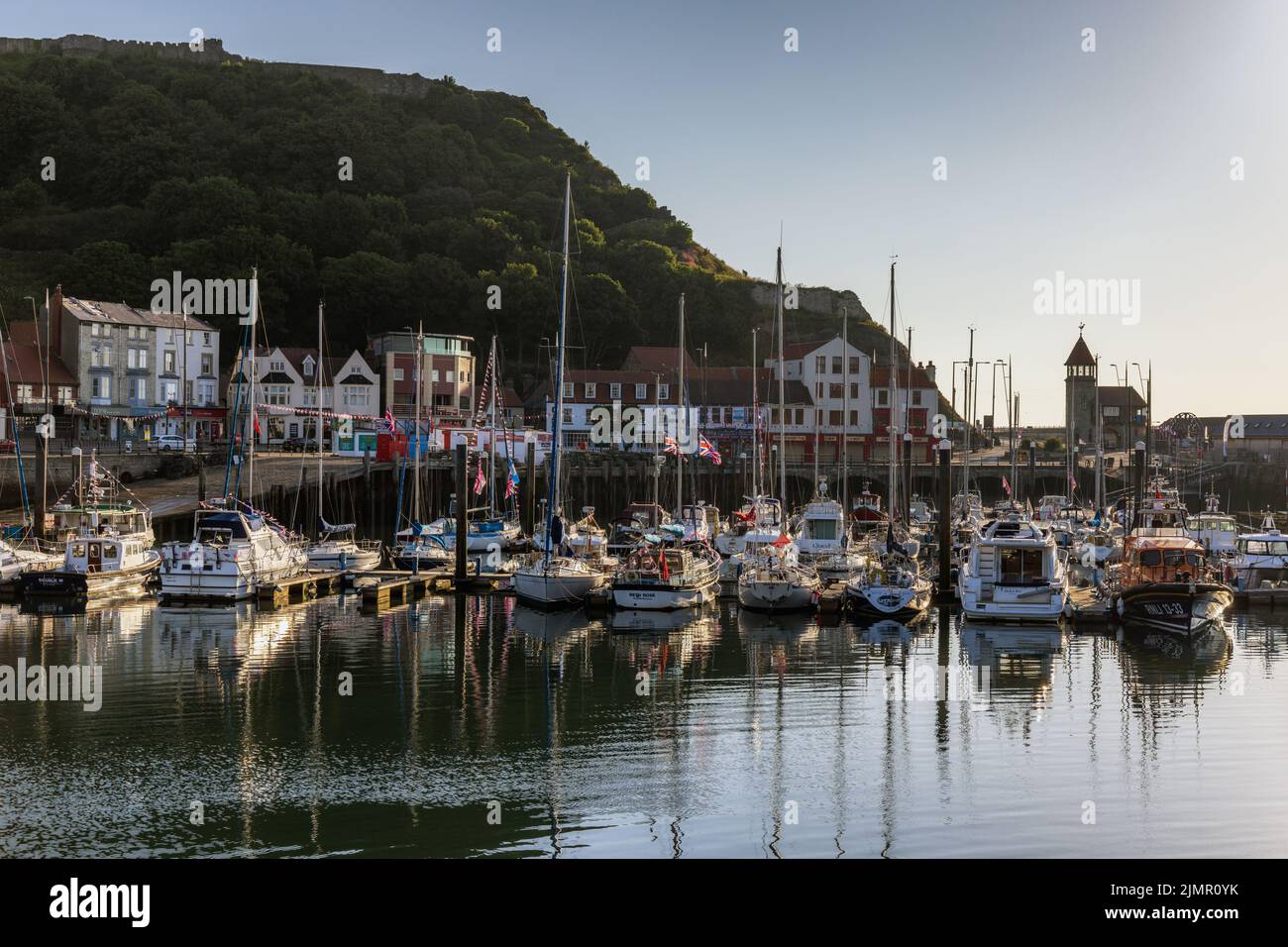 Early morning sun lighting up the boats and yachts moored in Scarborough harbour, with Scarborough Castle in the background. Stock Photo