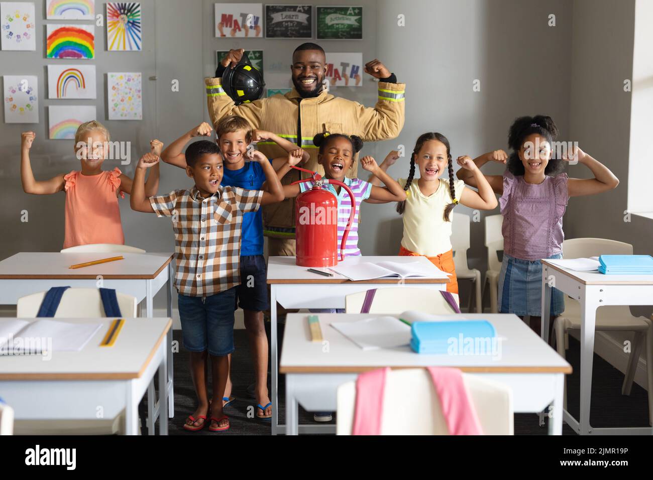 Multiracial elementary students and african american young male teacher flexing muscles Stock Photo