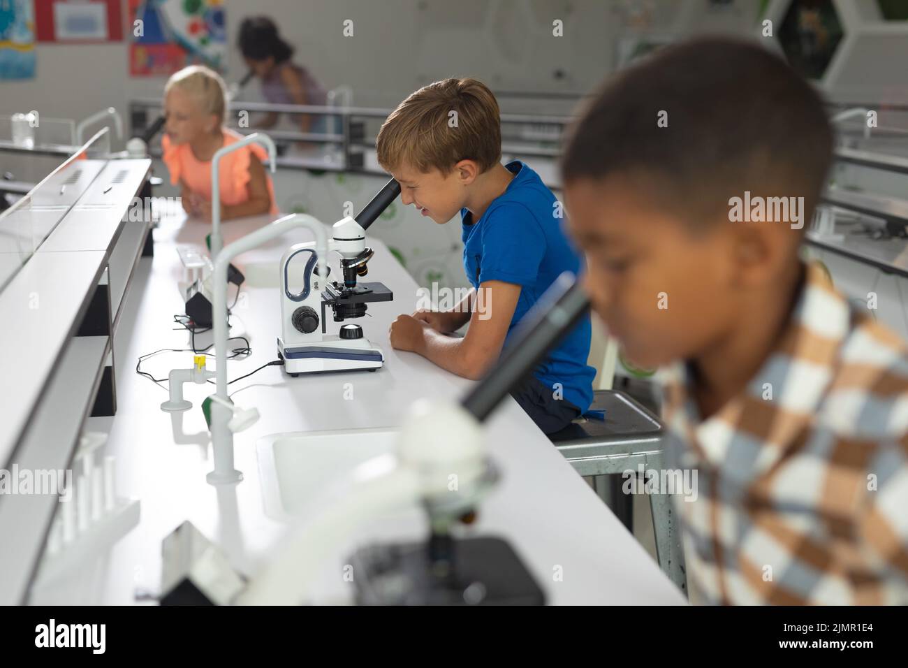 Multiracial elementary students looking in microscope during science