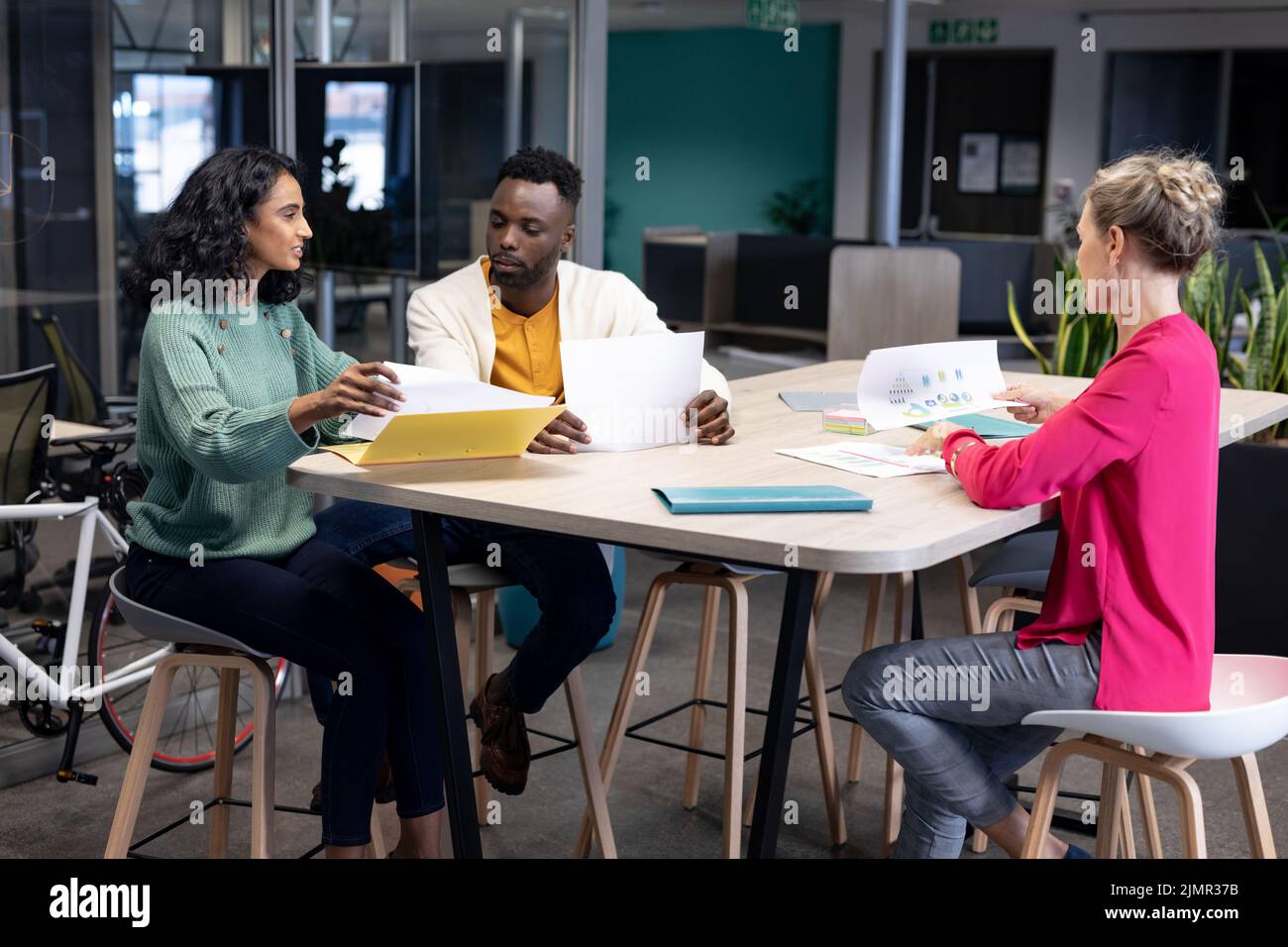 Biracial business colleagues discussing over document during meeting in ...