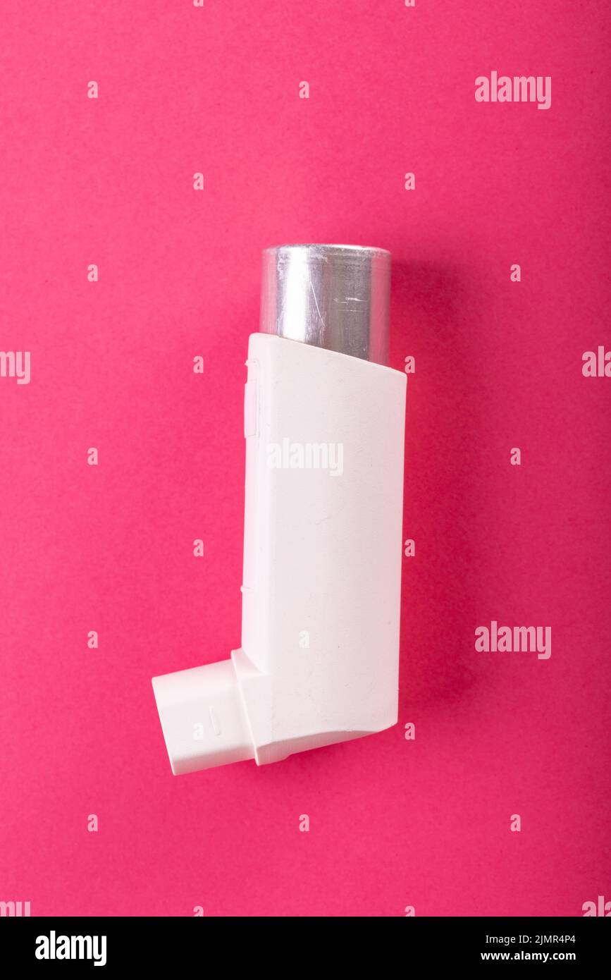 Close-up of white asthma inhaler isolated against pink background, copy ...