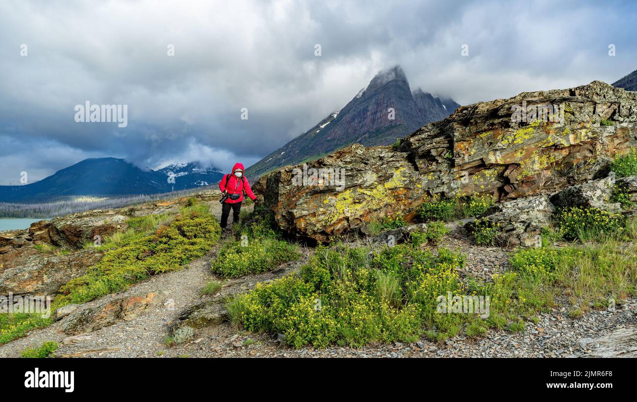 Person with red coat in Glacier National Park carrying a camera Stock Photo