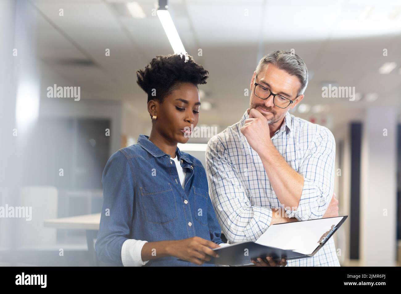 Confident biracial colleagues planning together while discussing over file at modern workplace Stock Photo