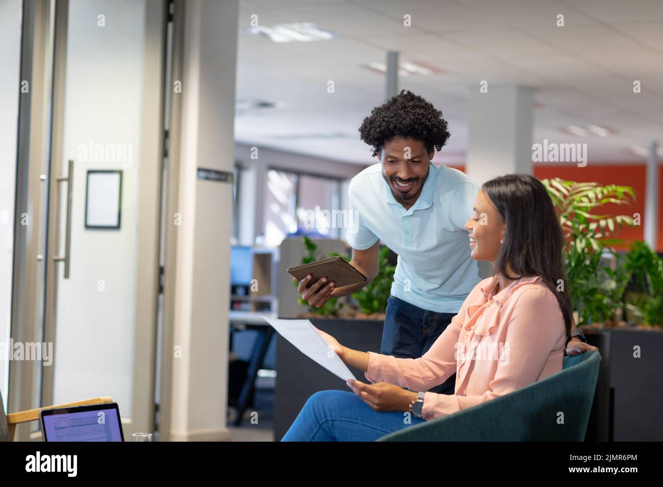 Smiling multiracial professionals discussing over document at modern workplace Stock Photo