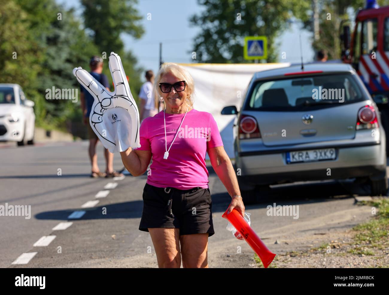 Krakow, Poland - August 5, 2022:  An elderly woman is cheering for the cyclists on the route of Tour de Pologne UCI – World Tour, stage 7 Skawina - Krakow. The biggest cycling event in Eastern Europe. Stock Photo