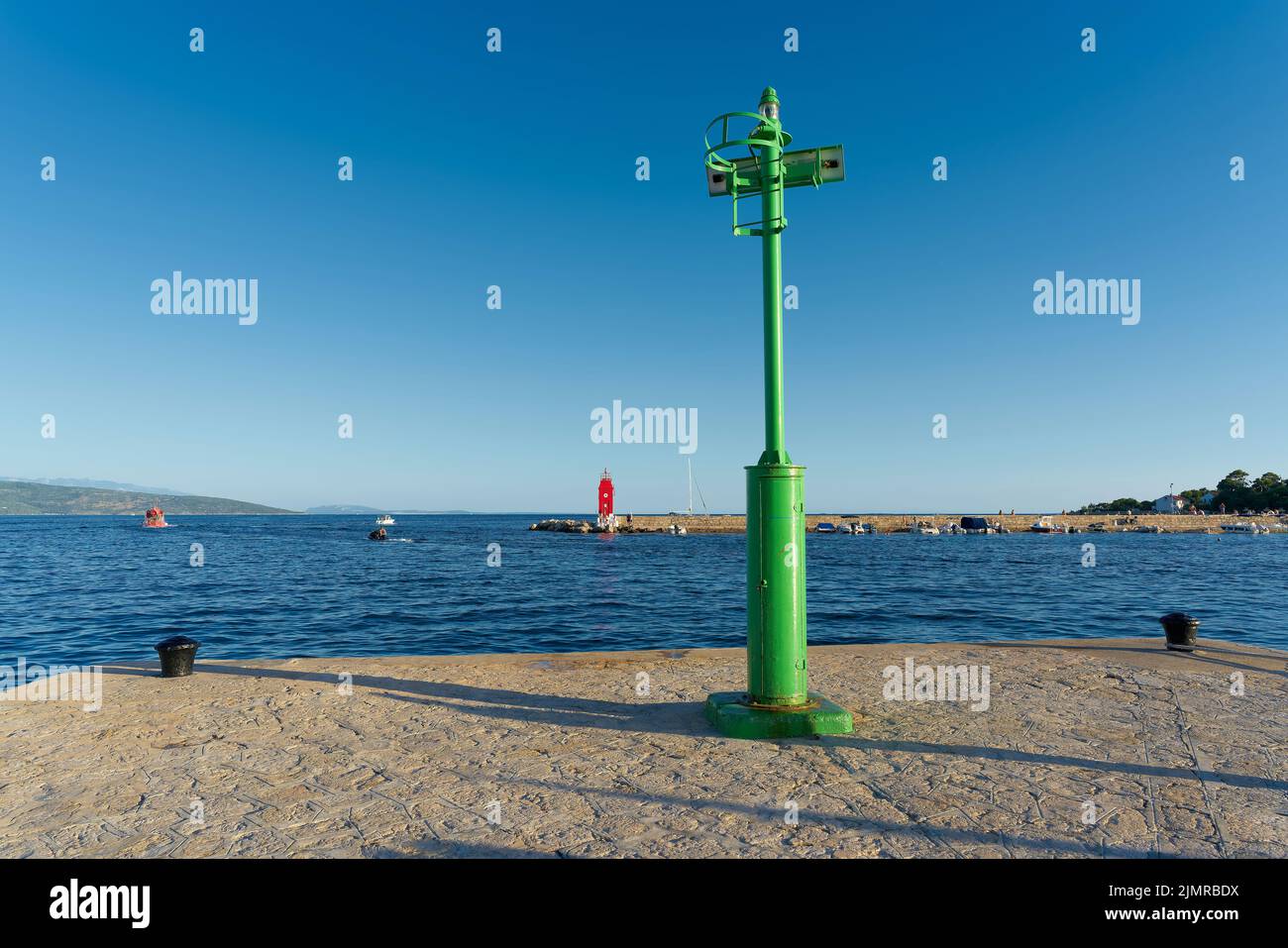 Green Lighthouse at a pier in the port of Krk on the Adriatic Sea in Croatia Stock Photo