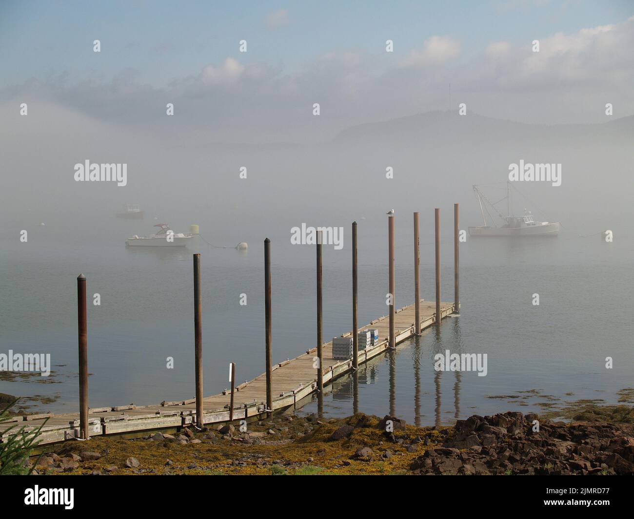 Early morning fog settles in on fishing boat and dock,coastal Maine Stock Photo