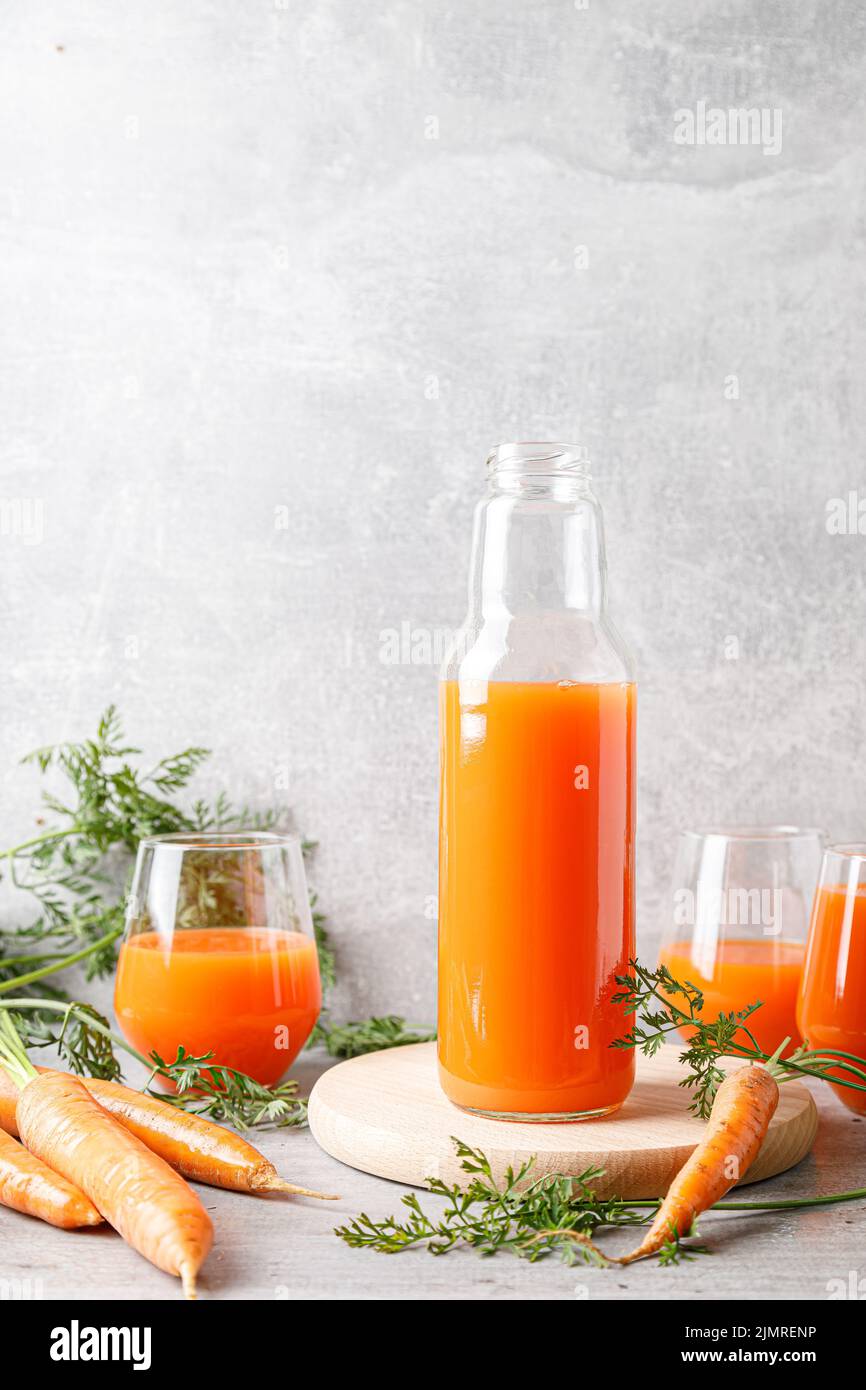 Carrot juice in a glass and bottle and fresh carrots with leaves Stock