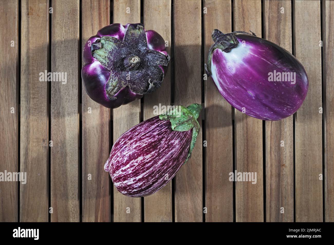 Composition of three round purple eggplants aubergine on wood background Stock Photo