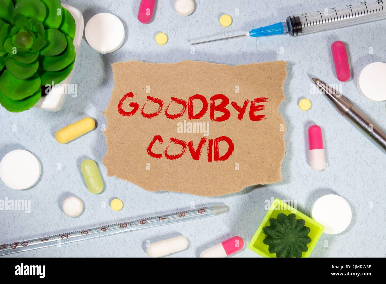 On a light blue background a card with the tex. GOODBYE CORONAVIRUS near the white bottle pills. Stock Photo