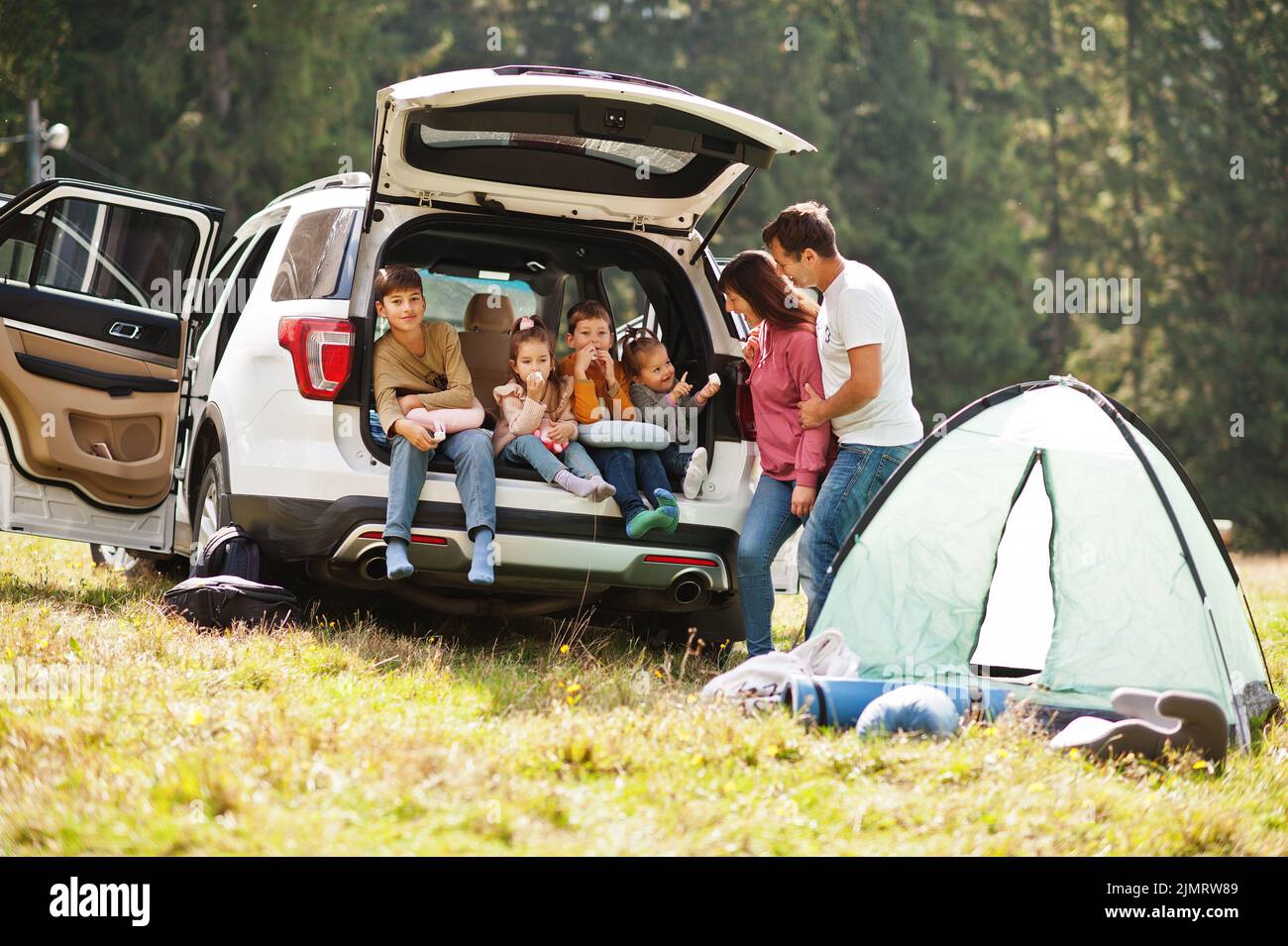Large family of four kids. Children in trunk. Traveling by car in the mountains, atmosphere concept. American spirit. Stock Photo